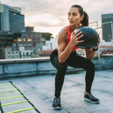 woman squatting holding medicine ball