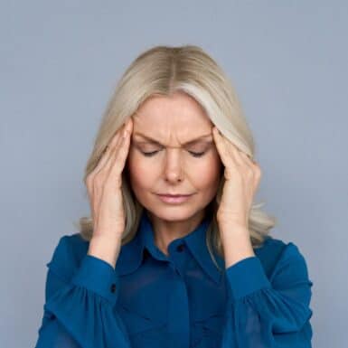 woman holding head with eyes closed frustrated with brain fog