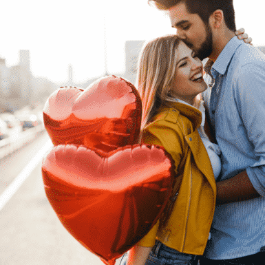 woman holding heart balloons next to a man